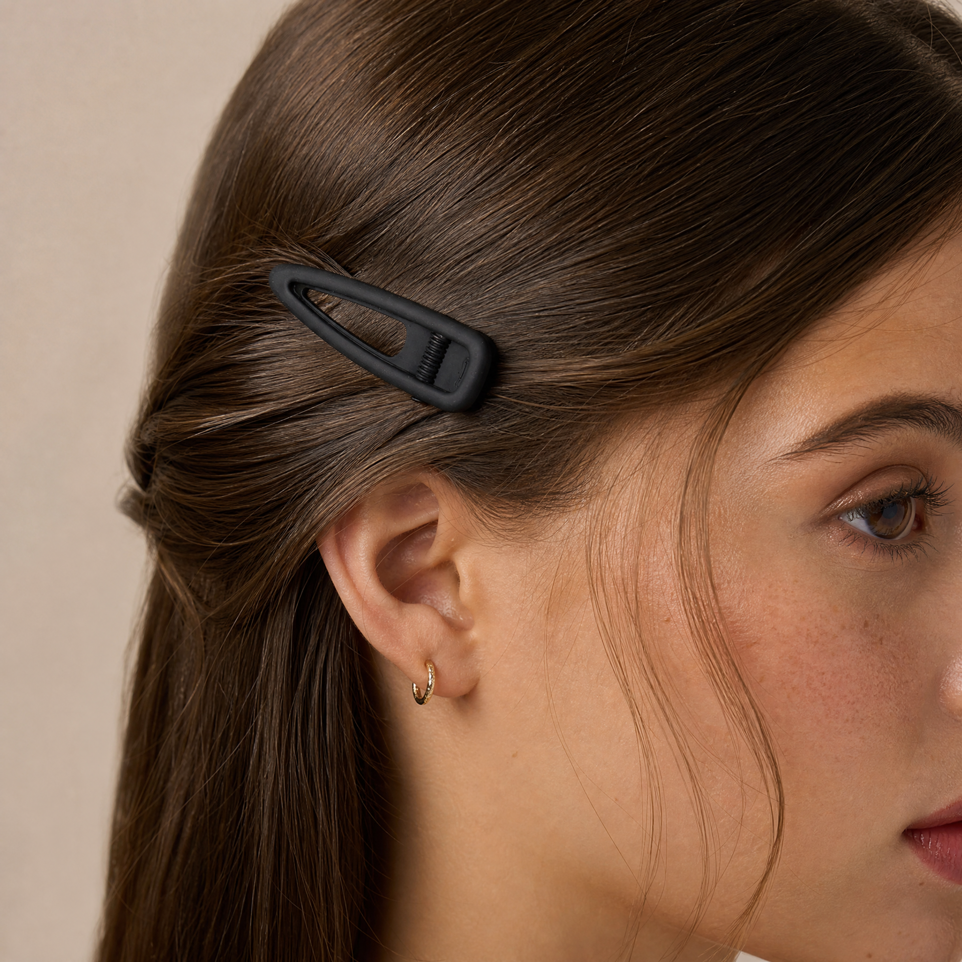 Close-up of a woman's hair with a black hair clip on a neutral background