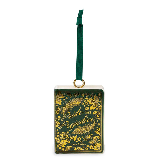 A rectangular Christmas ornament styled like a vintage book cover, featuring a dark green background with gold floral illustrations and the title 'Pride and Prejudice' in gold script. It has a white top border, a gold hanging ring, and a dark green hanging ribbon.
