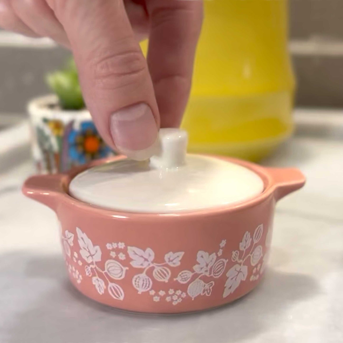 Tiny pink ceramic casserole with floral patterns on a white surface