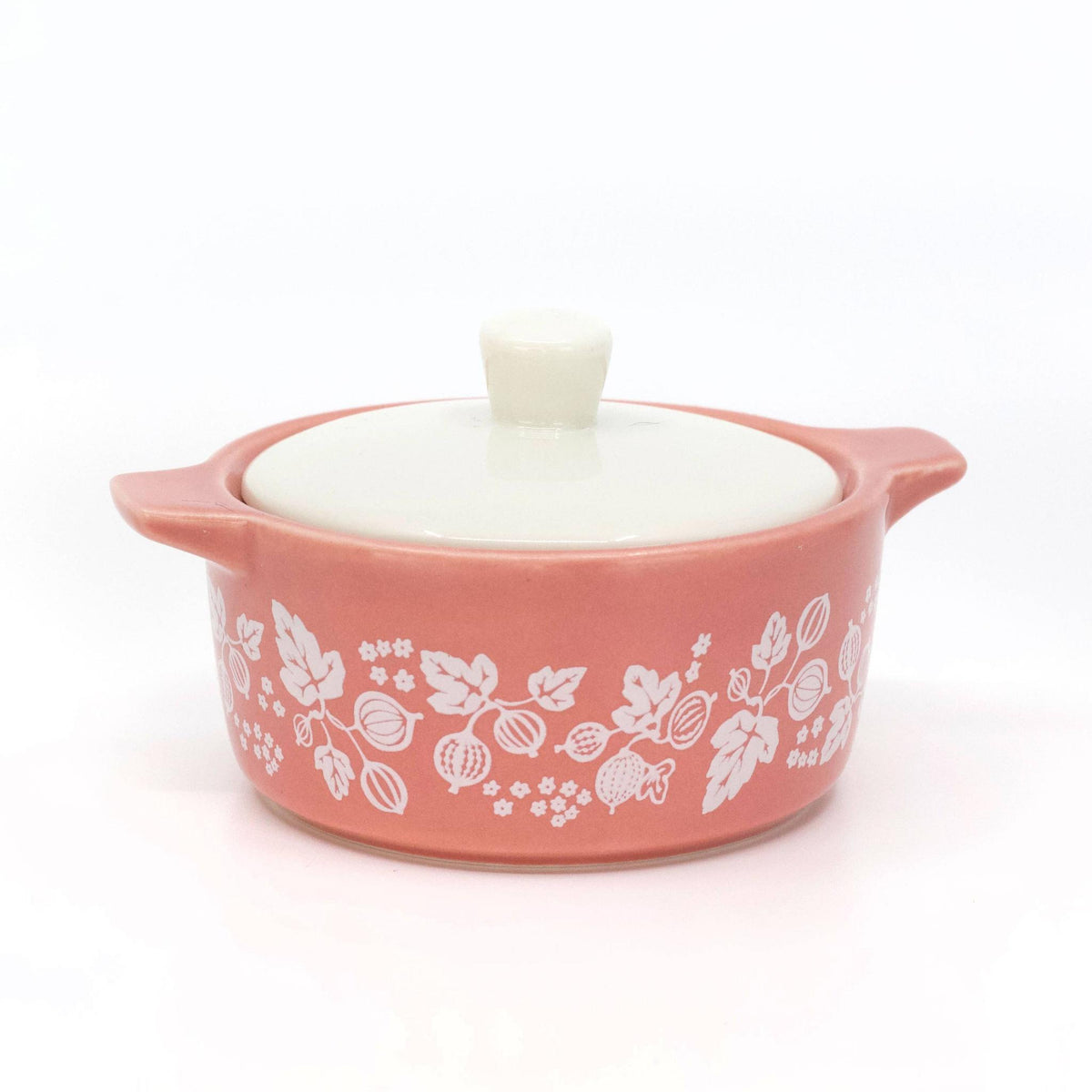 Small pink ceramic dish with white floral patterns and a white lid on a white background