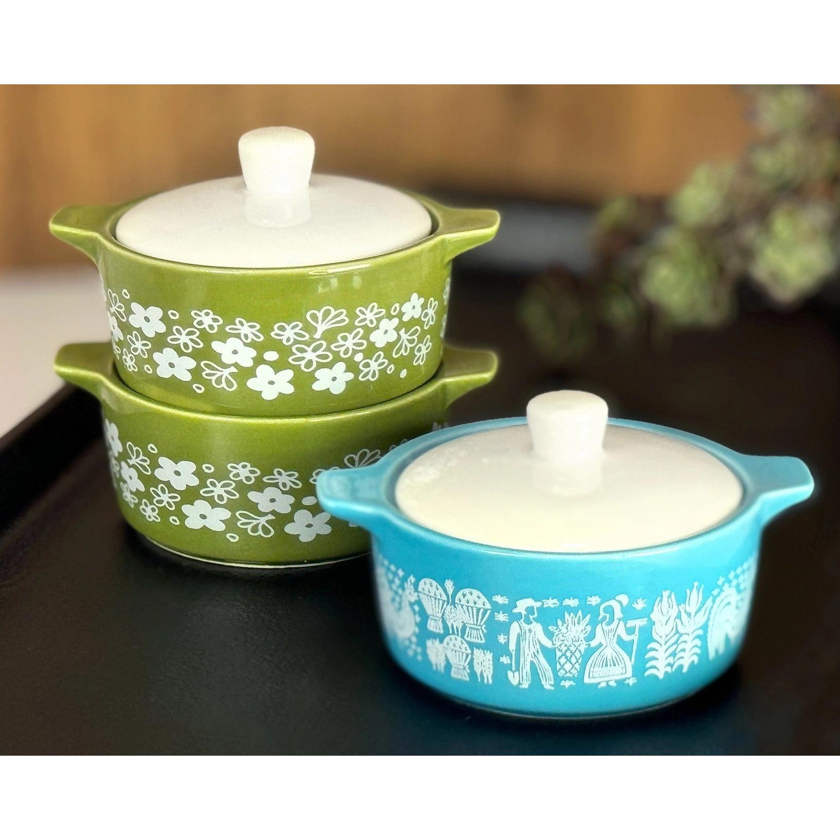 Two ceramic containers with floral patterns, one green and one blue, on a dark surface.