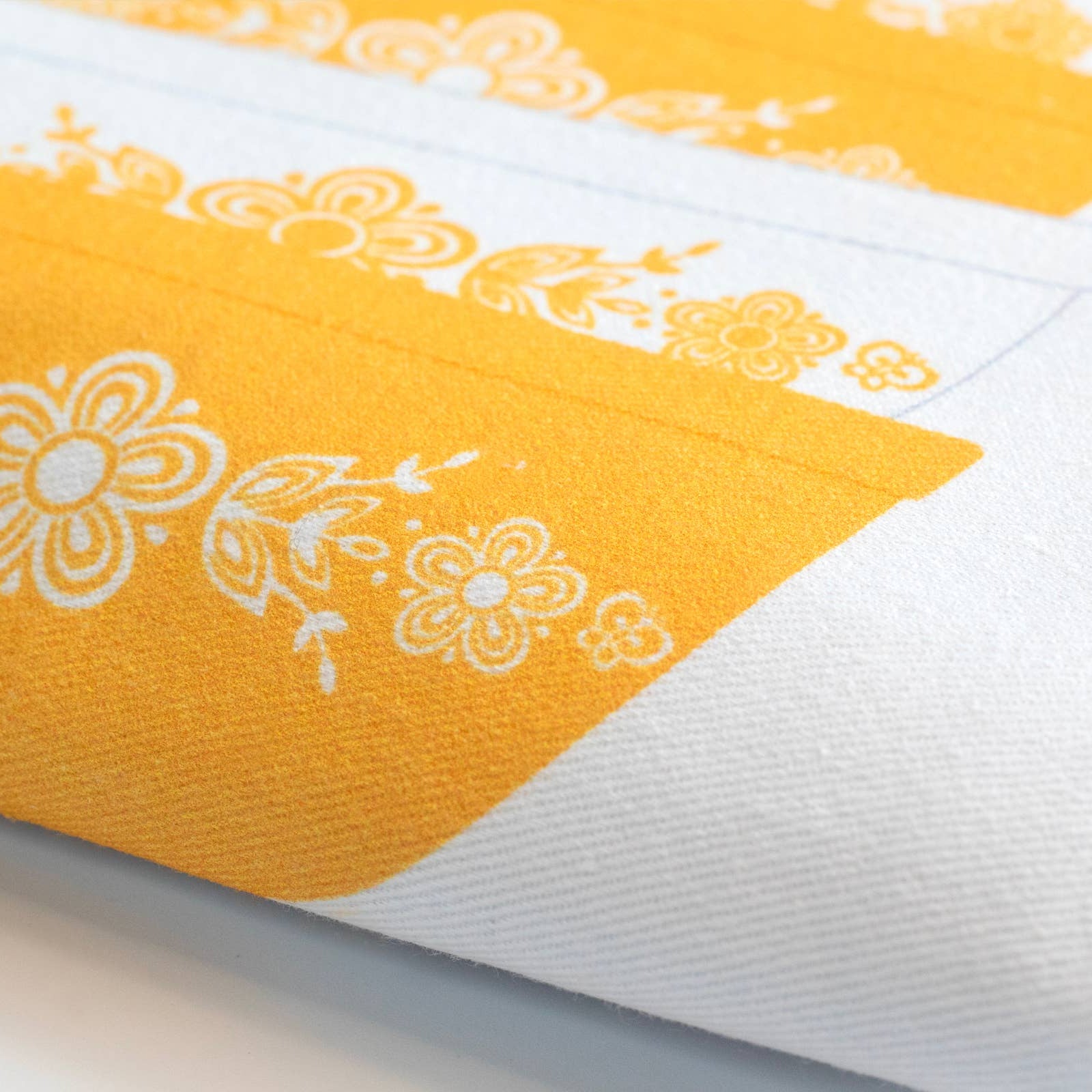 Yellow and white dish towel with floral patterns on a light background
