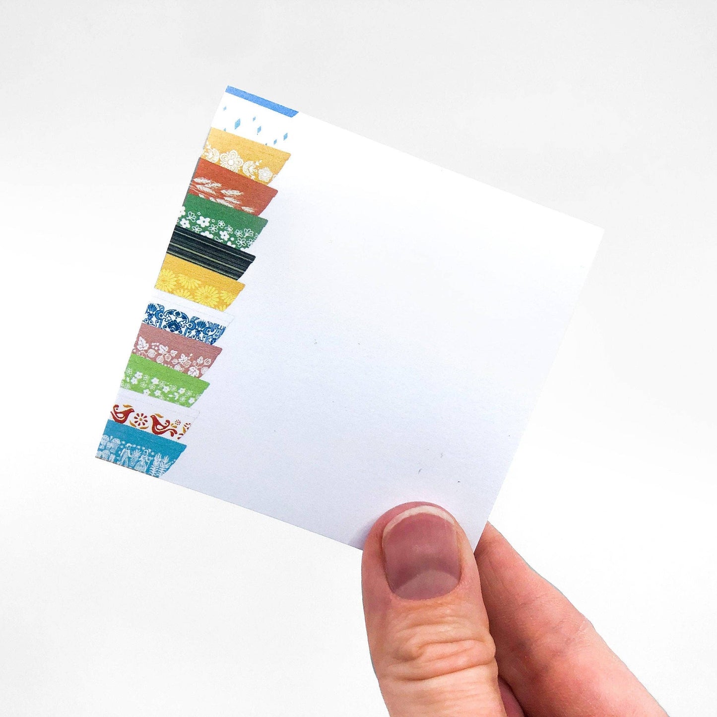 Hand holding sticky notes with Pyrex-inspired bowls illustration on a white background