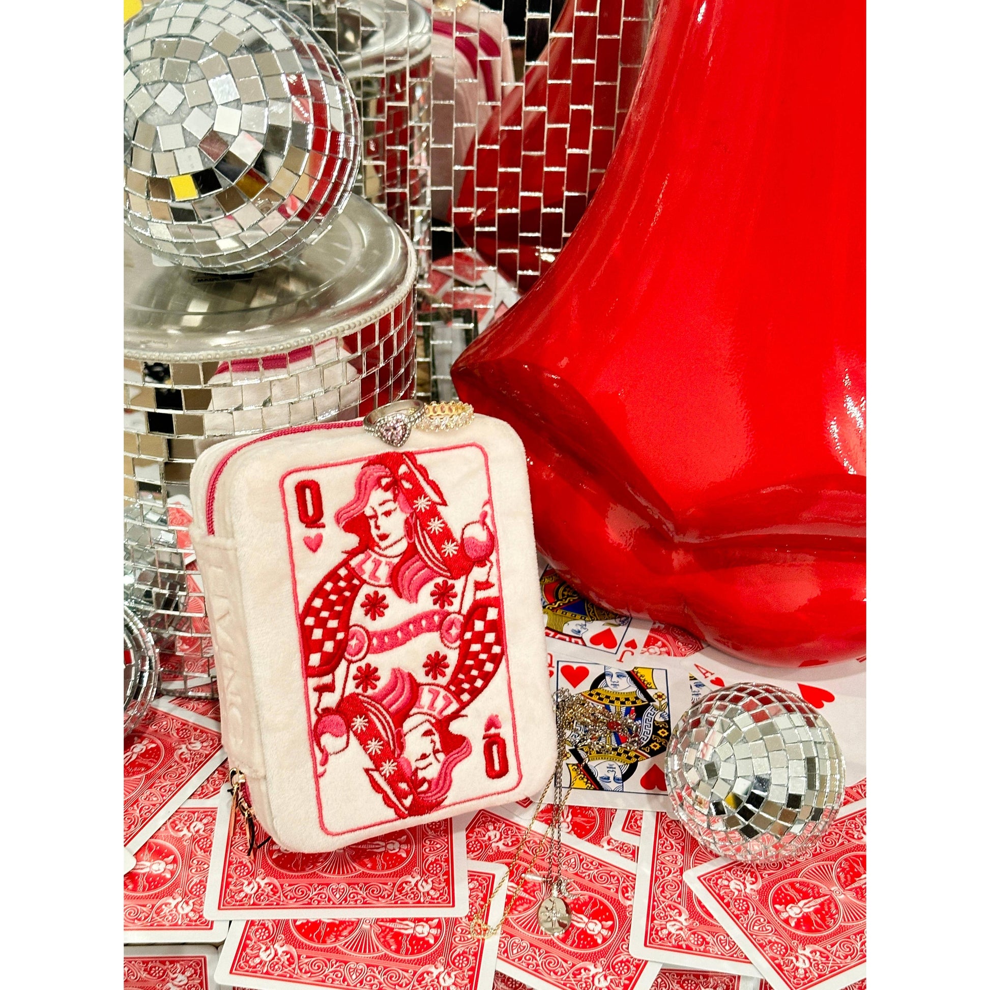 Queen of Hearts card purse on playing cards with disco balls and red heart-shaped object.
