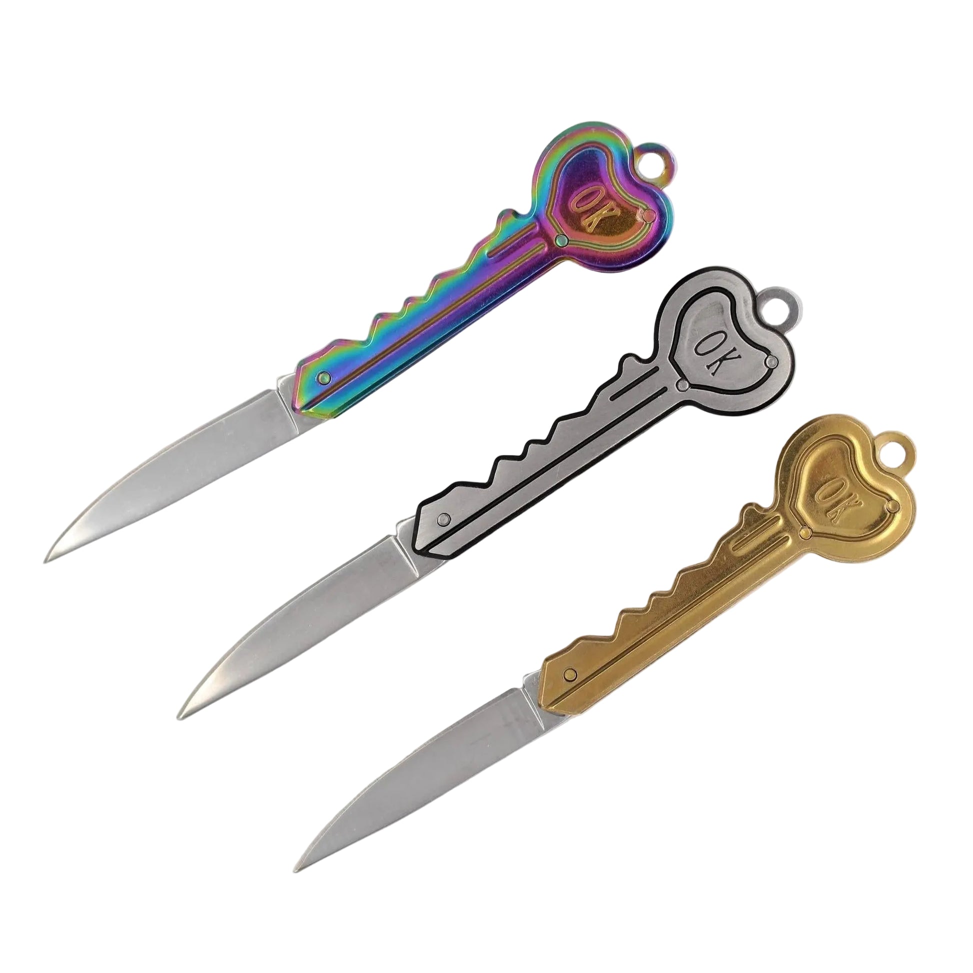 Three key-shaped letter opener knives with silver blades are arranged diagonally on a white background. The handles feature three different finishes: a vibrant iridescent rainbow sheen, a simple black outline, and a polished gold finish, each with a heart-shaped key bit engraved with 'OX'.