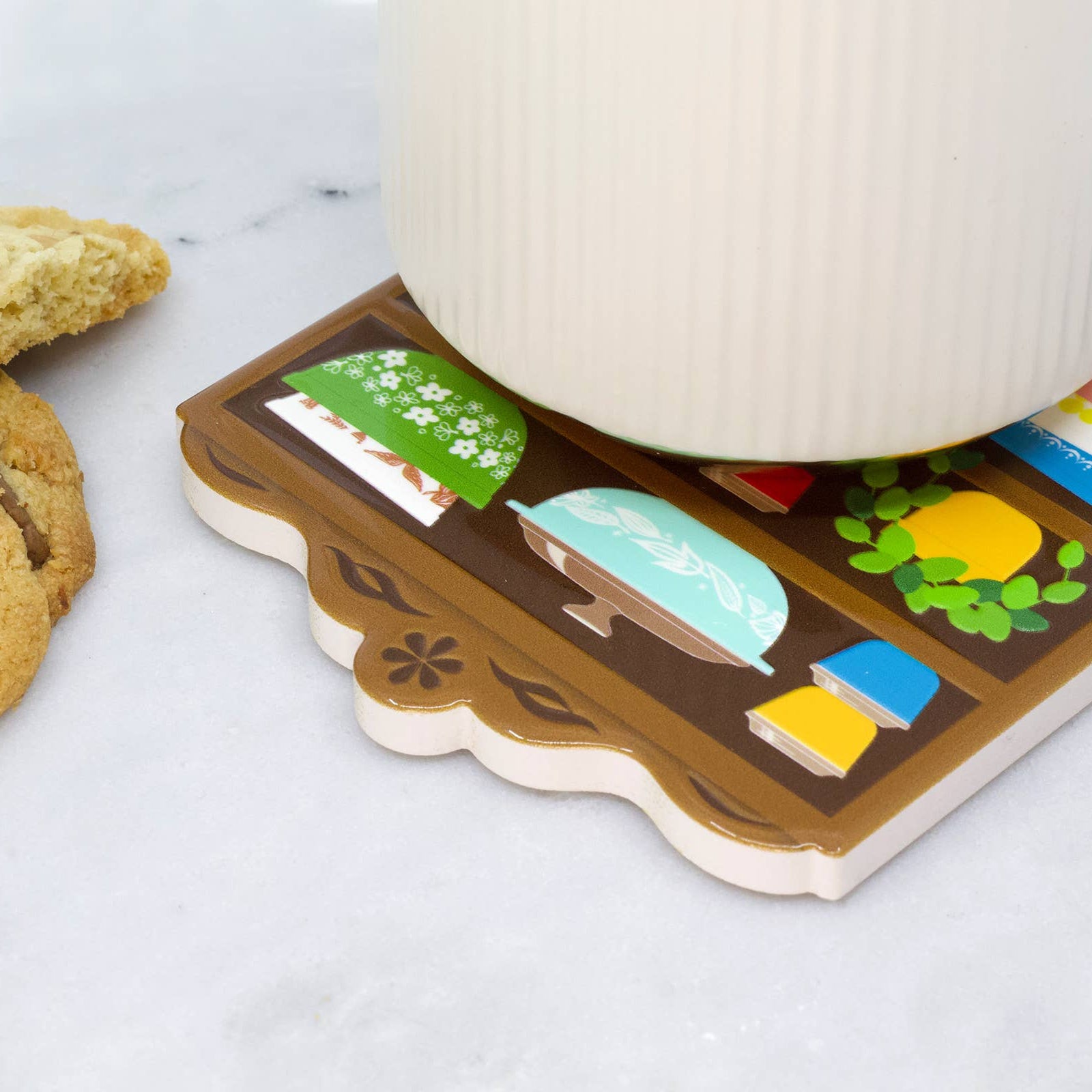 Coaster with bowl designs on a white surface with cookies and a mug.