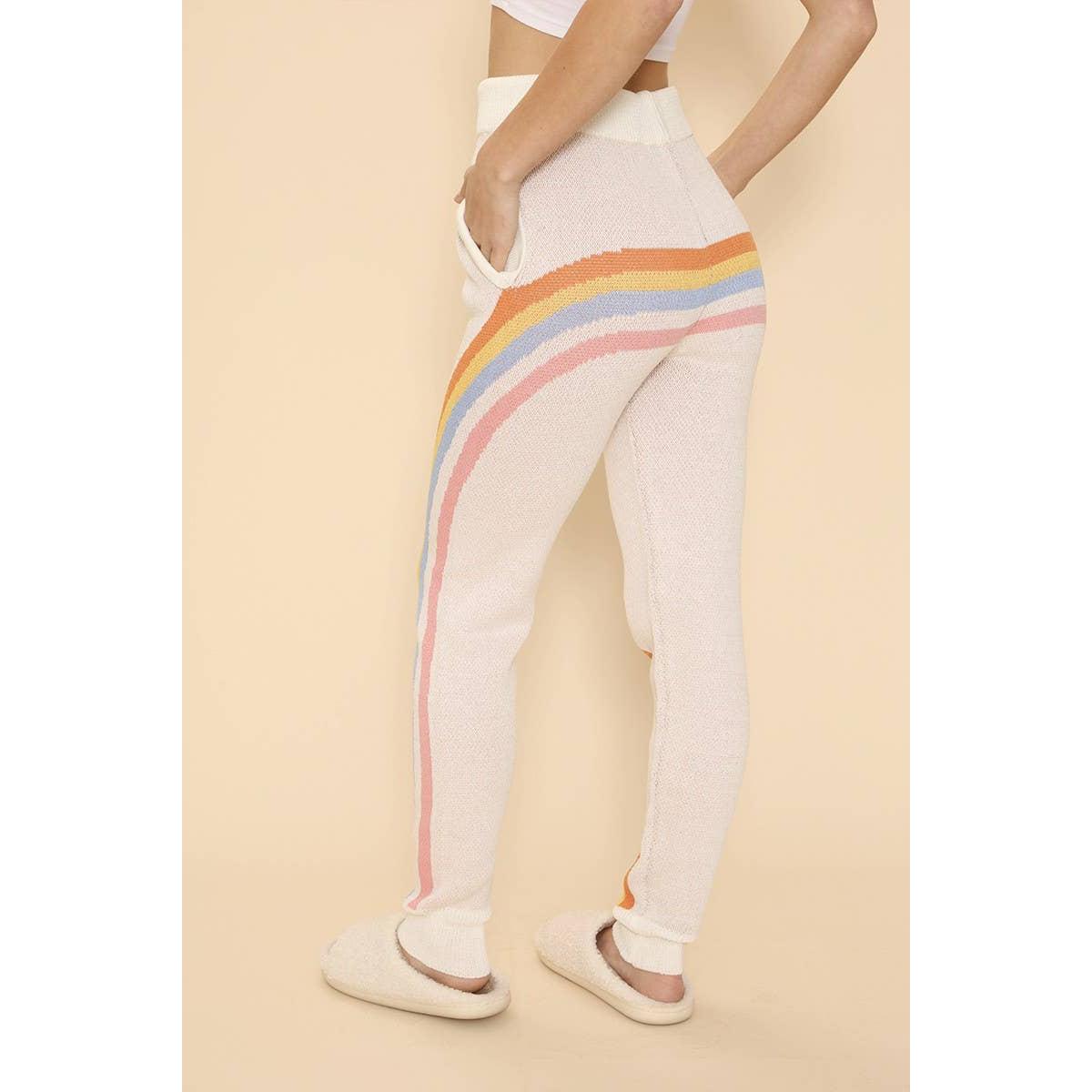White pants with rainbow stripes worn by a person on a beige background