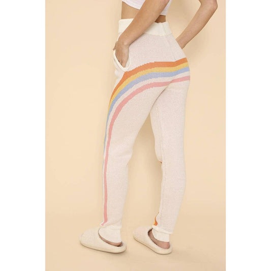 White pants with rainbow stripes worn by a person on a beige background