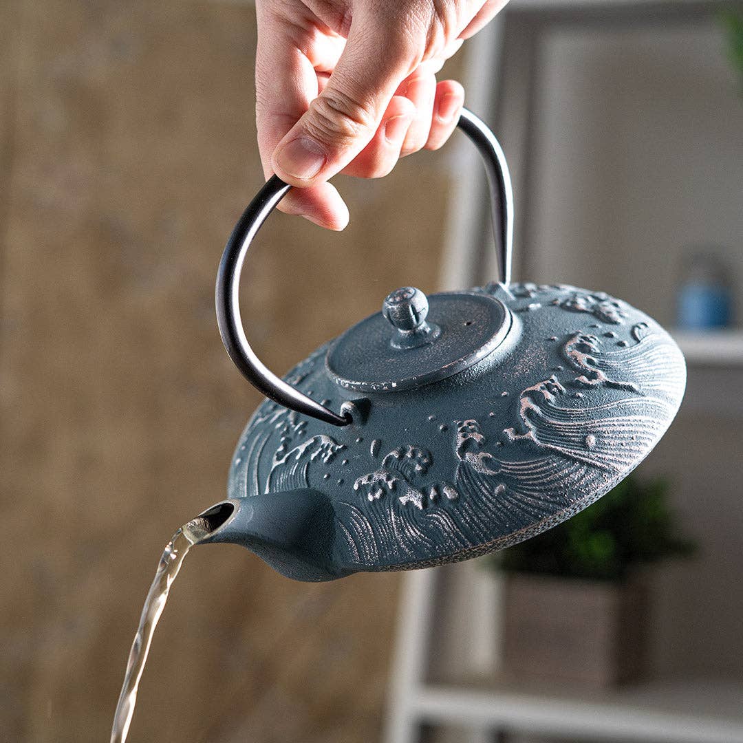 Cast iron teapot with wave design being filled with water
