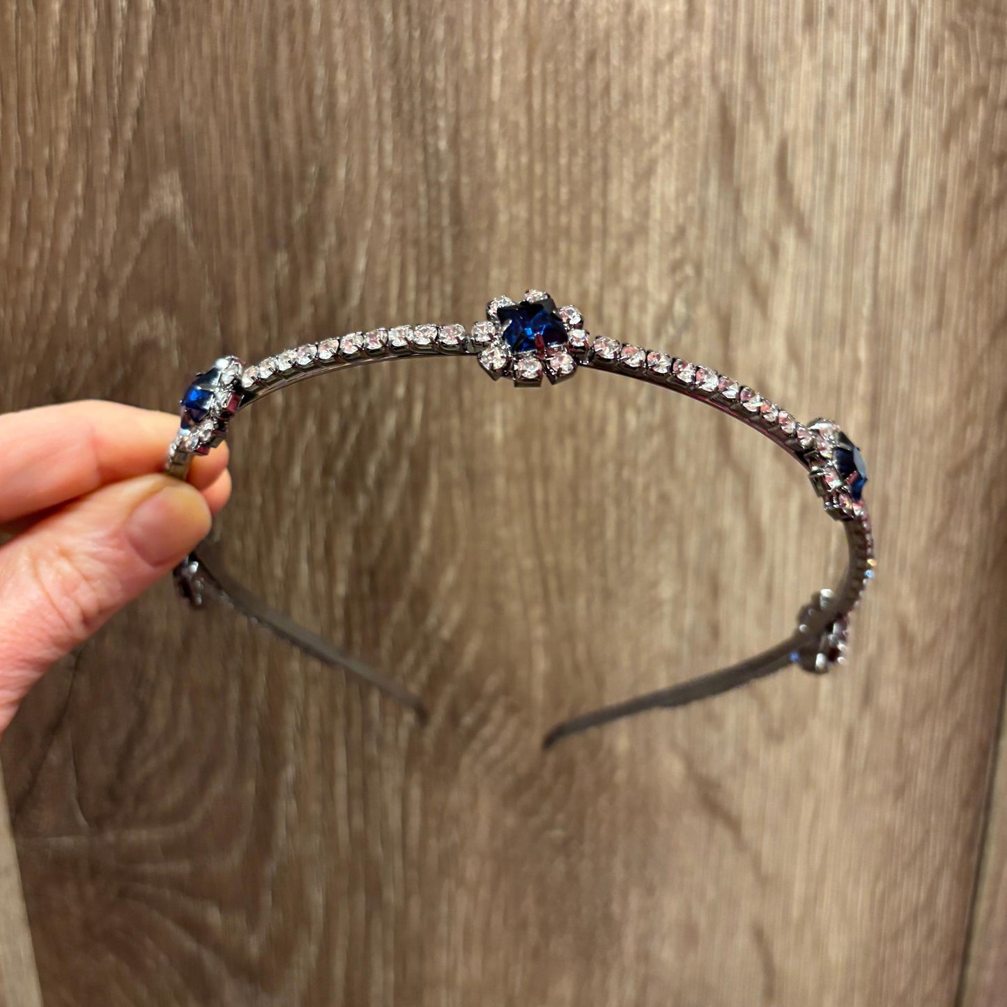 Beaded headband with blue stones held by a hand on a wooden surface