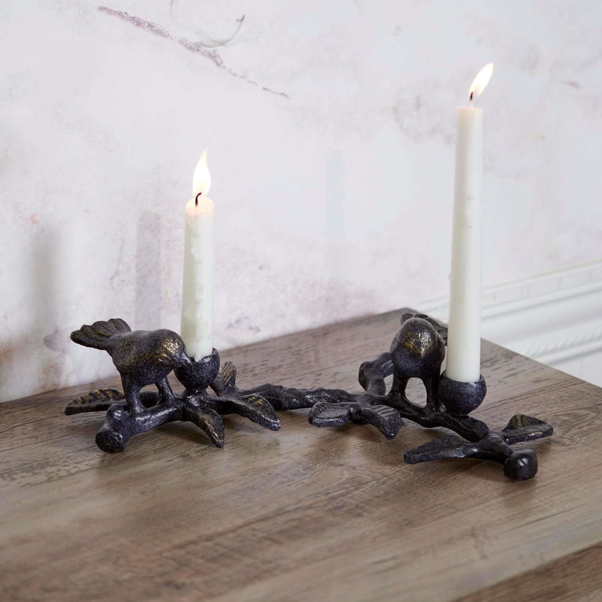 Decorative candle holders shaped as birds with lit candles on a wooden surface.