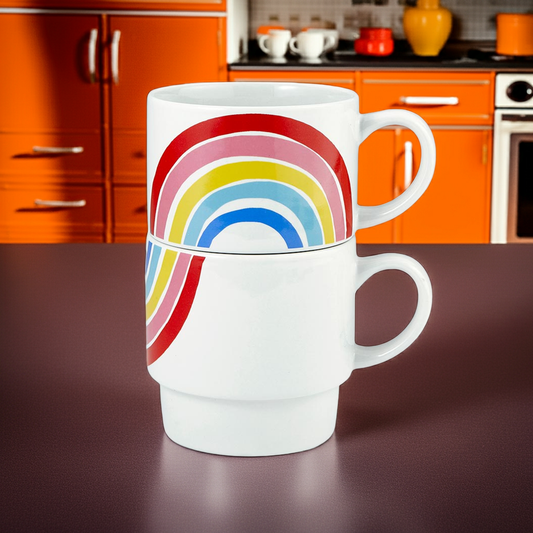 White mug with a colorful rainbow design on a dark surface, kitchen in the background