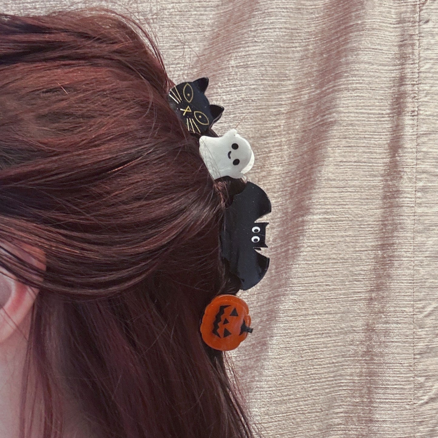 Halloween-themed hair clips on a person's hair against a neutral background