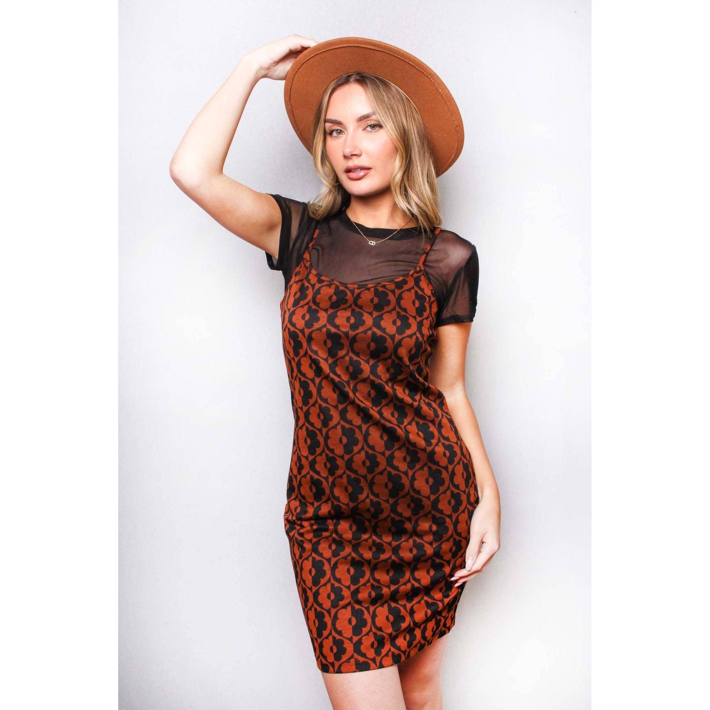 Woman wearing a patterned dress and brown hat against a white background