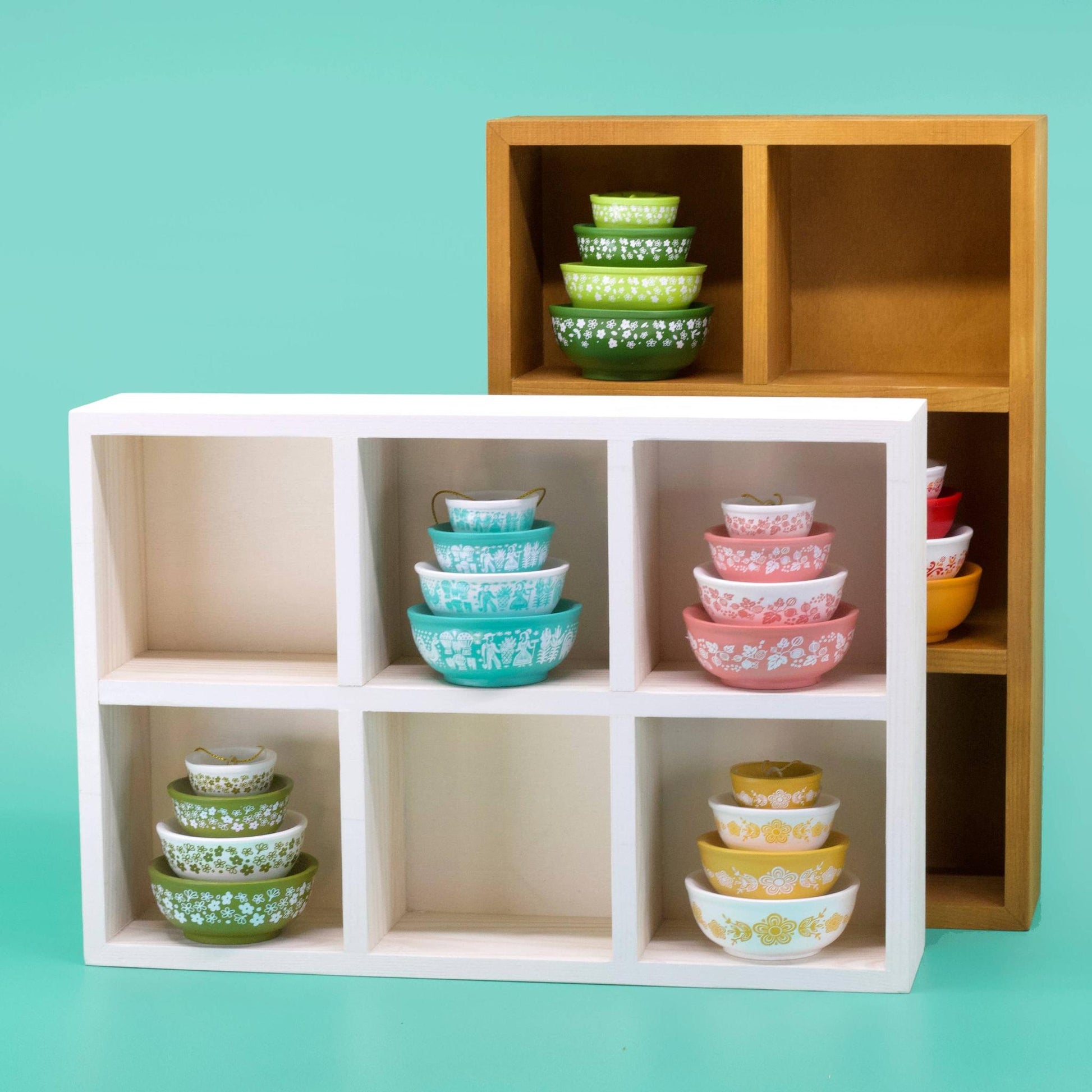 Stacked bowls on wooden and white shelves against a teal background