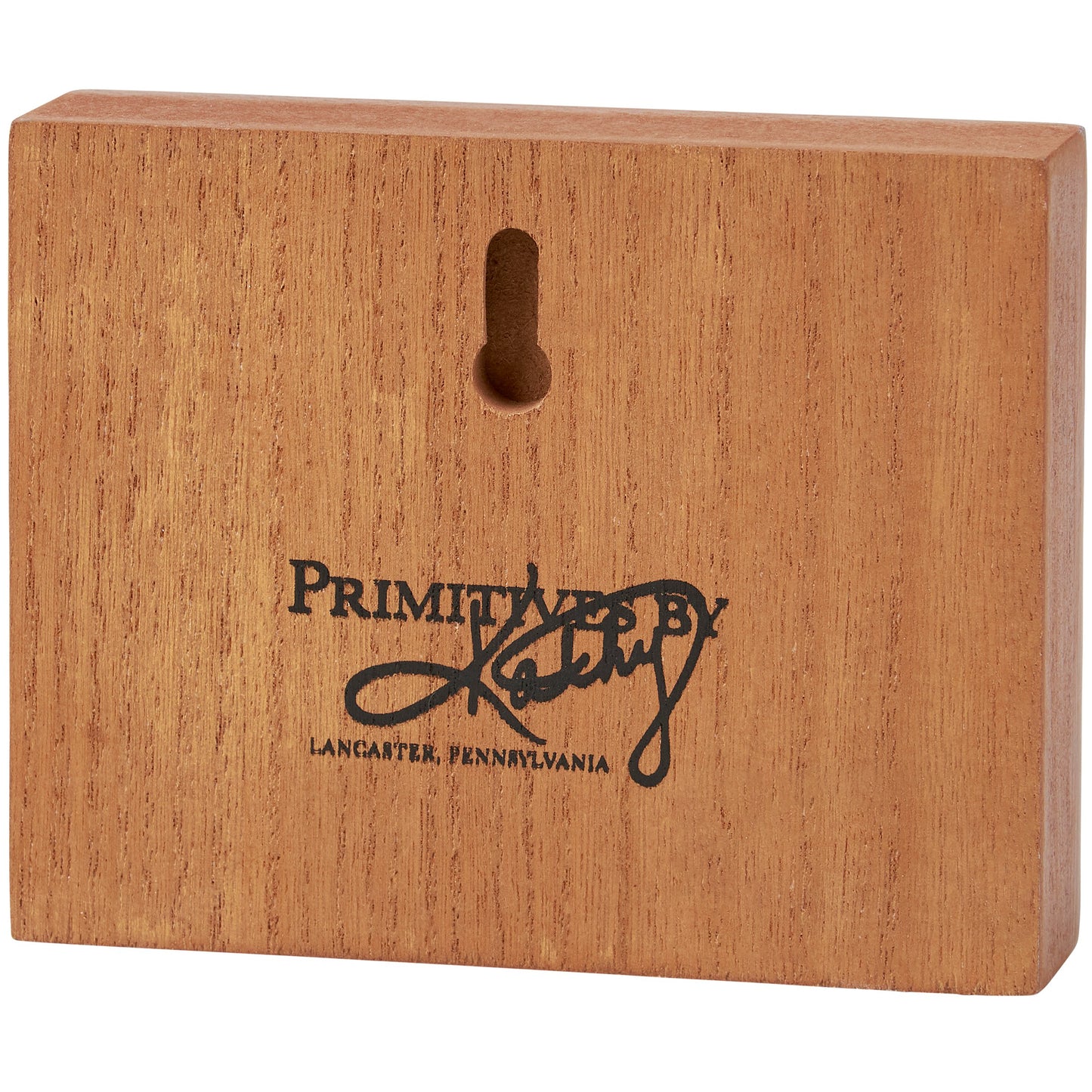 Wooden block with 'Primitives by Kathy' branding on a white background