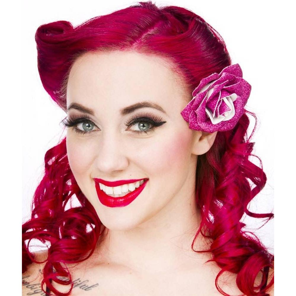 Woman with vibrant red hair and a pink flower accessory against a white background