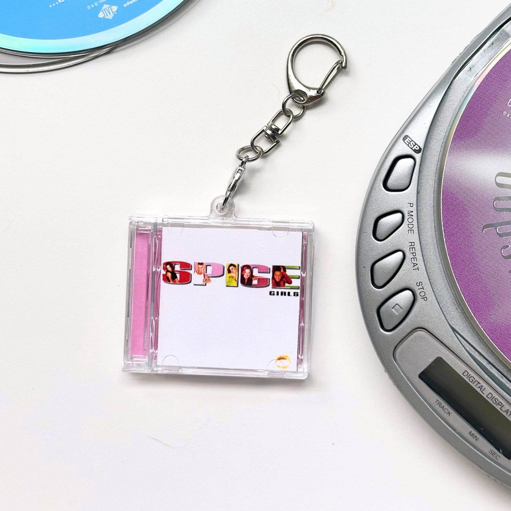 Spice Girls CD case shaped keychain  next to a digital music player