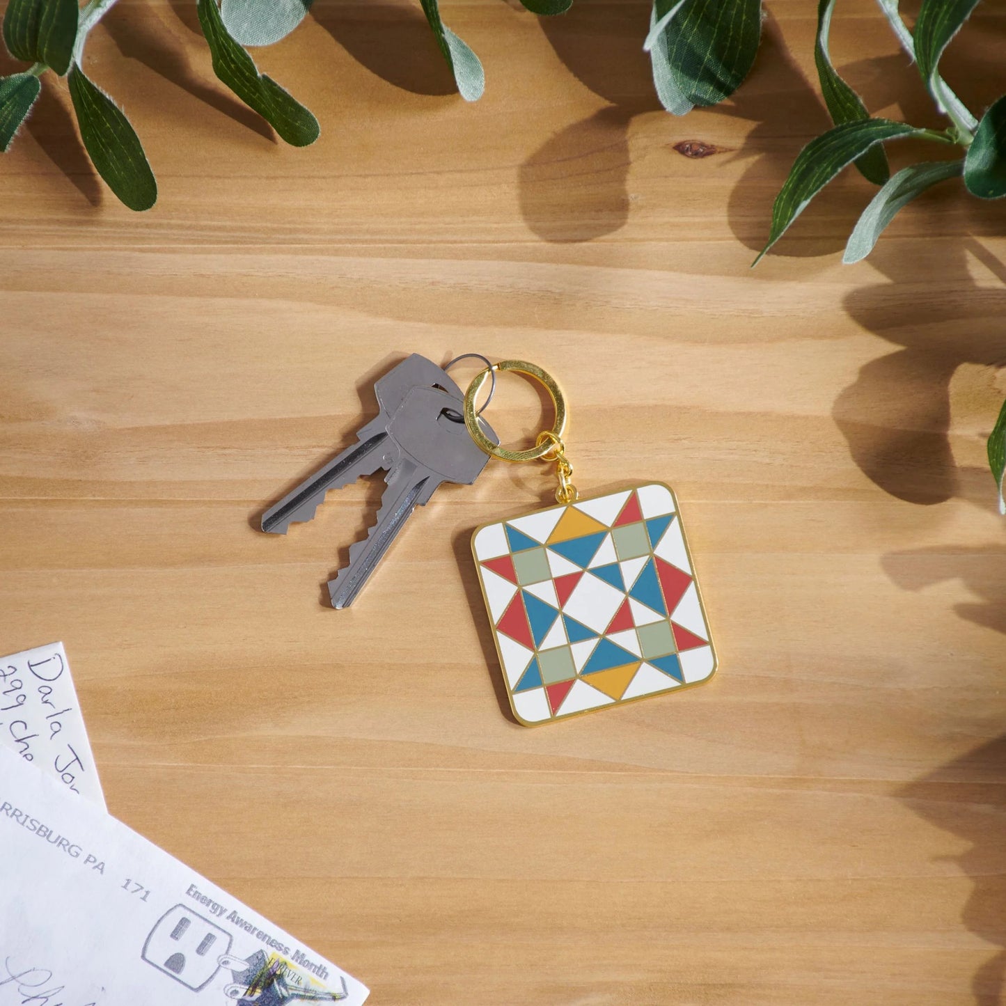 Keychain with geometric design on a wooden surface with leaves in the background