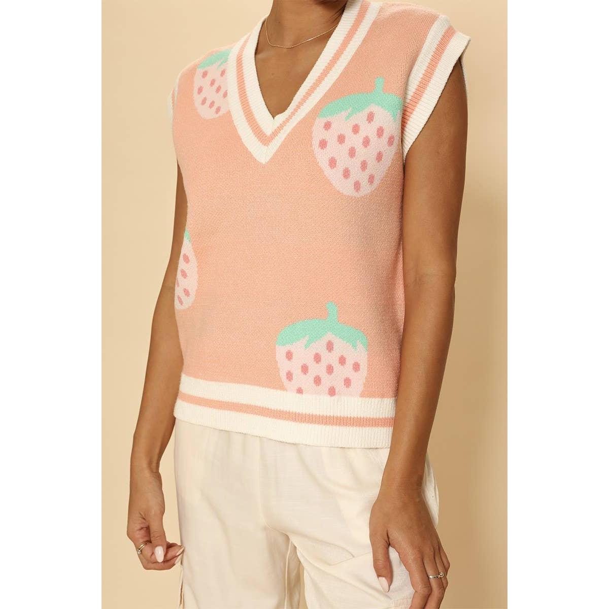 Person wearing a pink sleeveless sweater with strawberry patterns on a beige background
