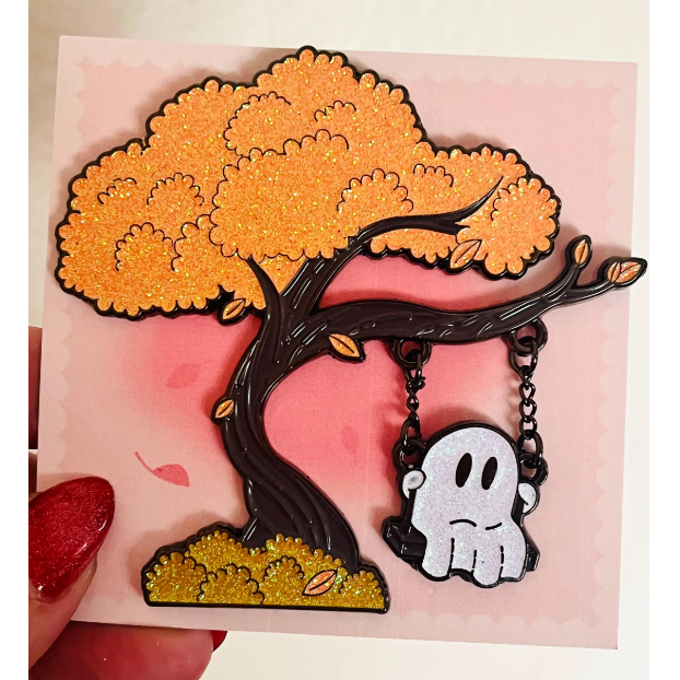Tree-shaped brooch with a ghost charm on a pink background