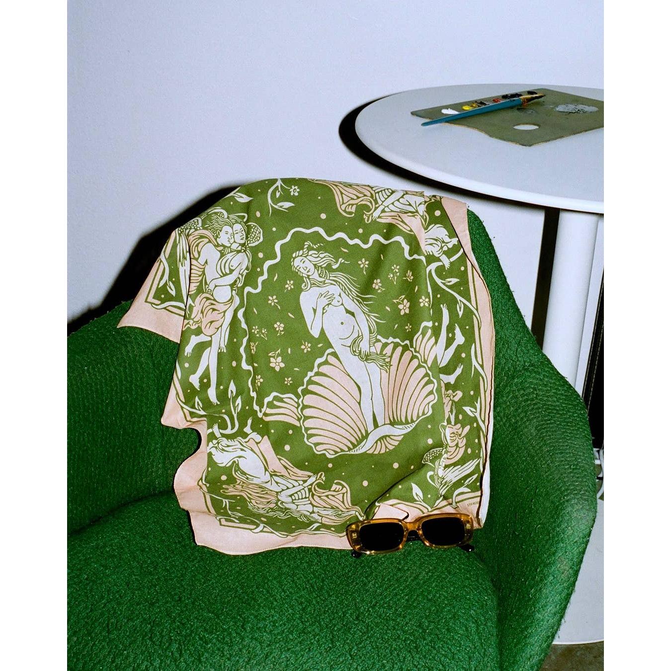 Green patterned scarf draped over a green chair with sunglasses