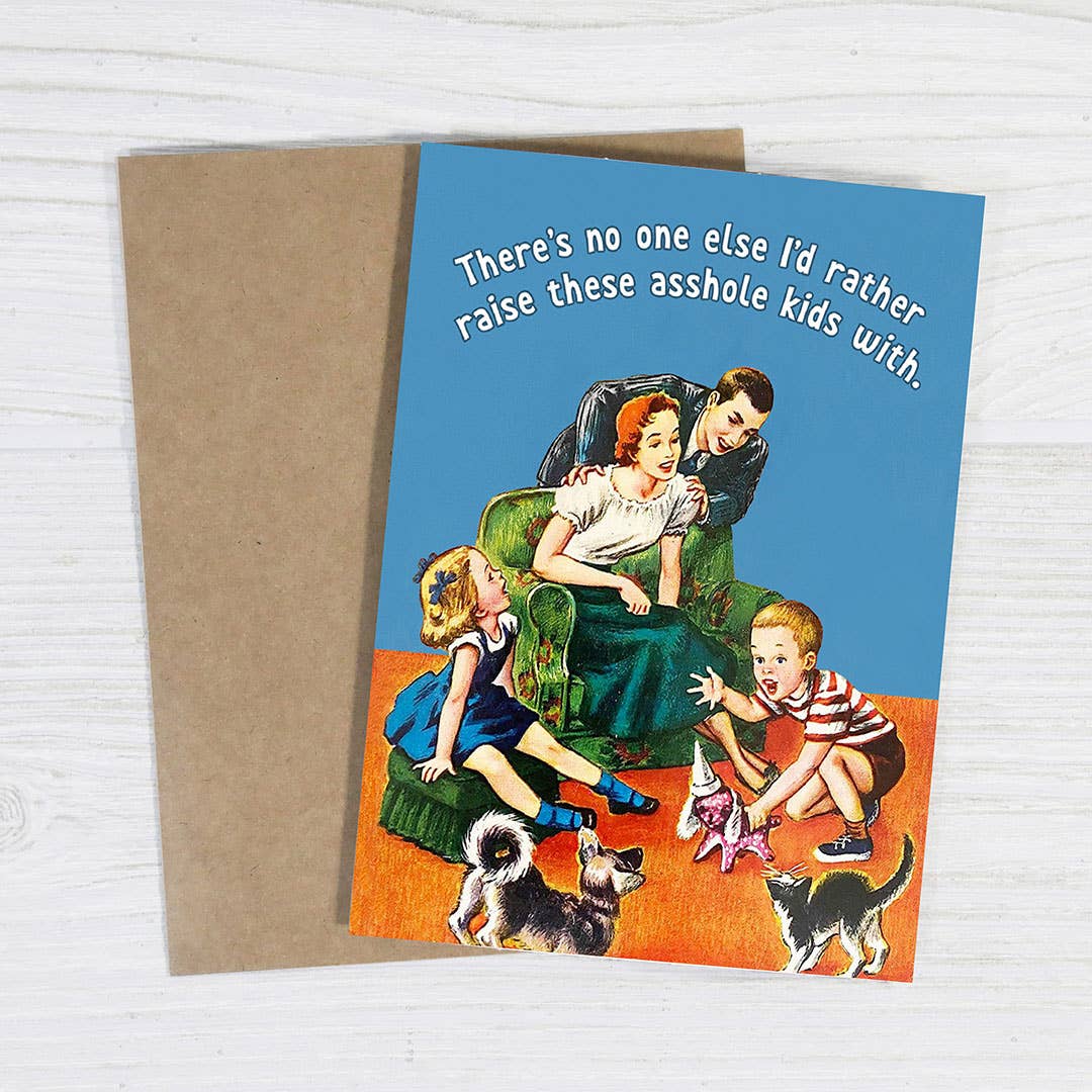 Card with a family scene and humorous text on a wooden surface