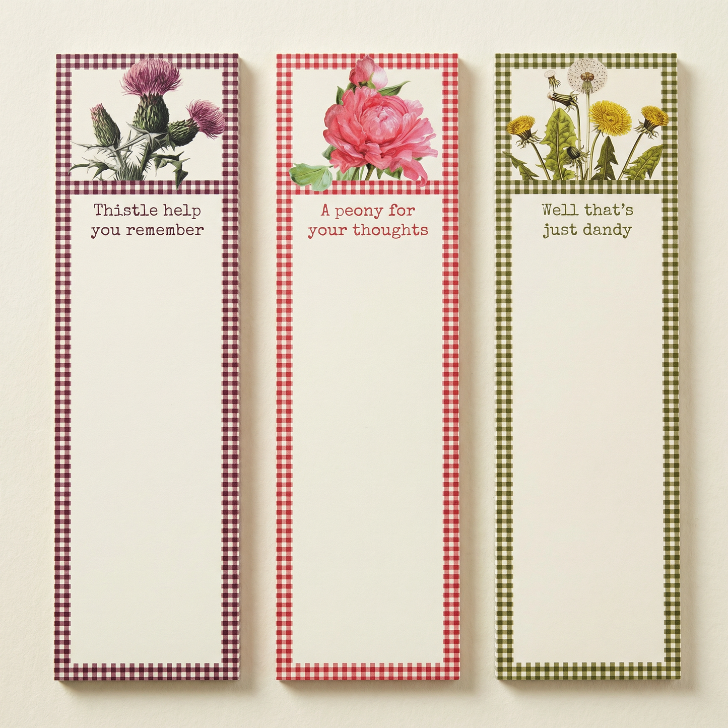 Three floral-themed notepads with checkered borders and text on a beige background
