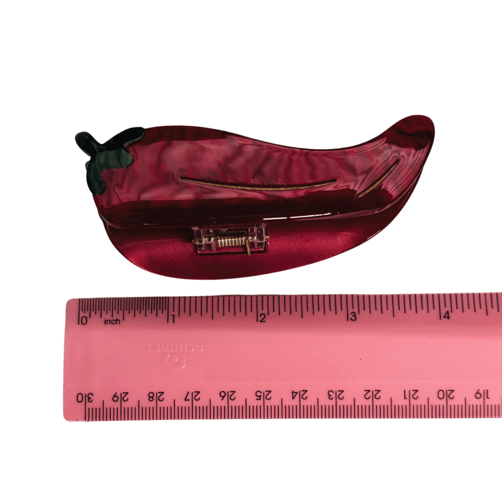 Red chili pepper-shaped hair jaw with a ruler for scale on a white background