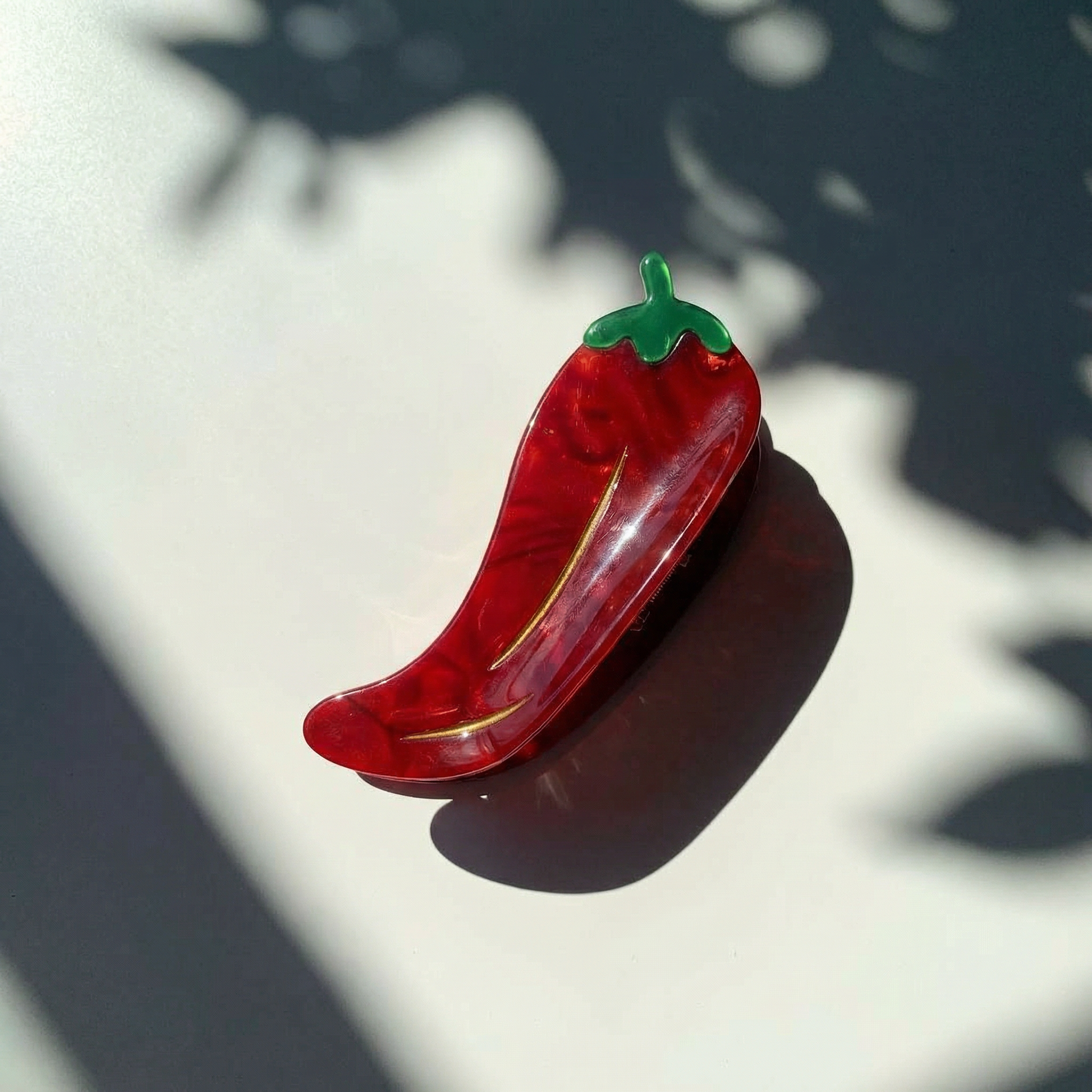 Red pepper-shaped hair claw with green top on a light background