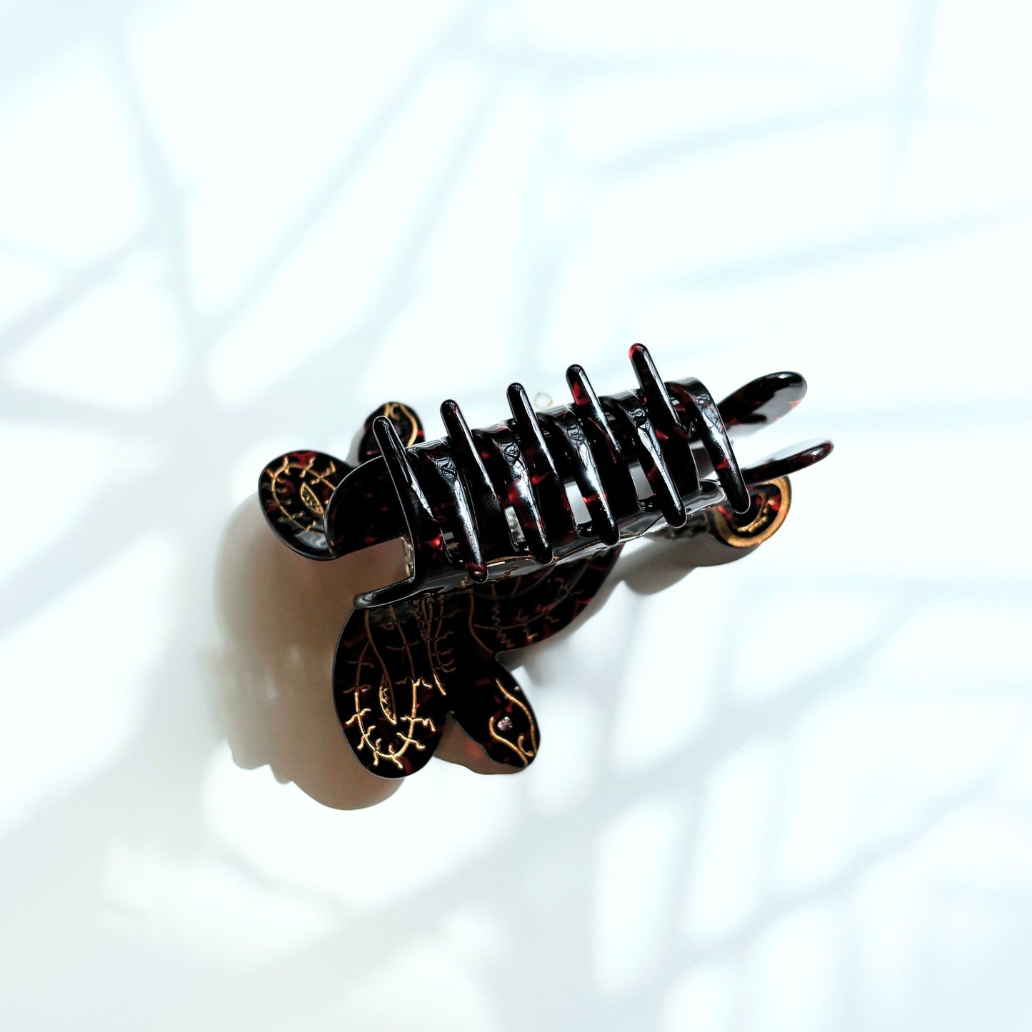 Black hair clip with decorative elements on a light blue background