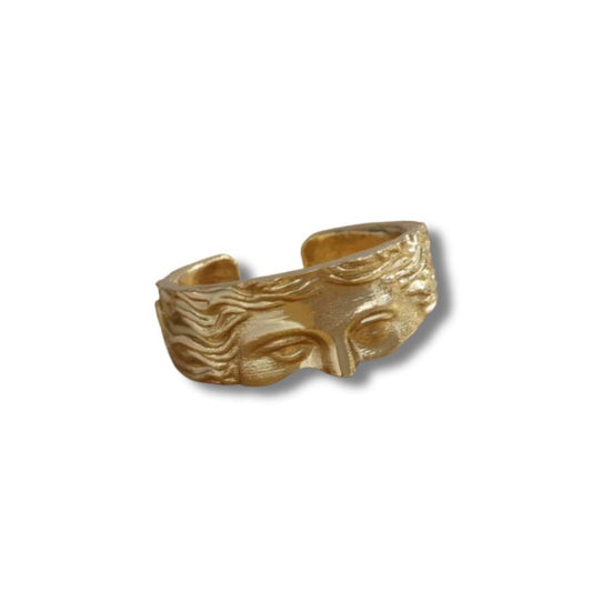 Gold ring with a face design on a white background
