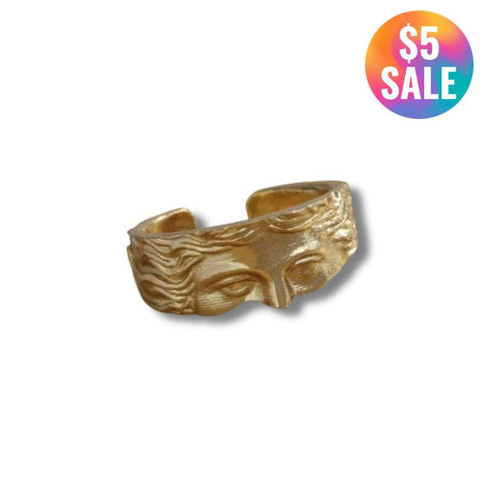 Gold ring with a face design on a white background