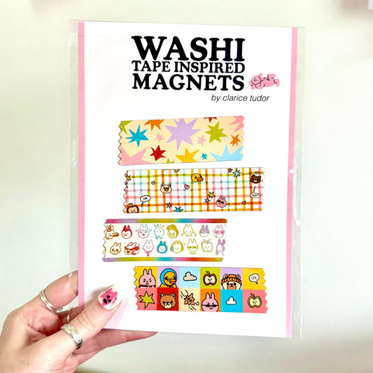 A hand holds a clear plastic sleeve containing a set of washi tape inspired magnets. The magnets feature various colorful washi tape patterns, including stars, plaid, and cartoon characters