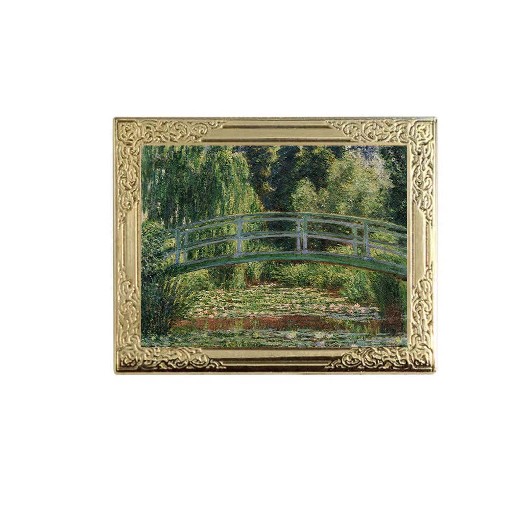 Lapel pin of framed painting of a bridge over water lilies with a gold frame