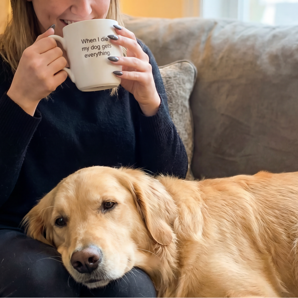 Woman sitting on a couch with a dog, holding a mug.