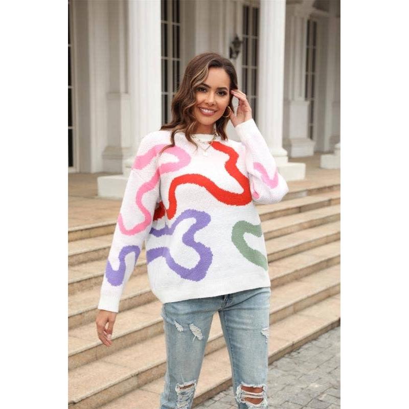 Woman wearing a colorful sweater with abstract patterns standing outdoors.