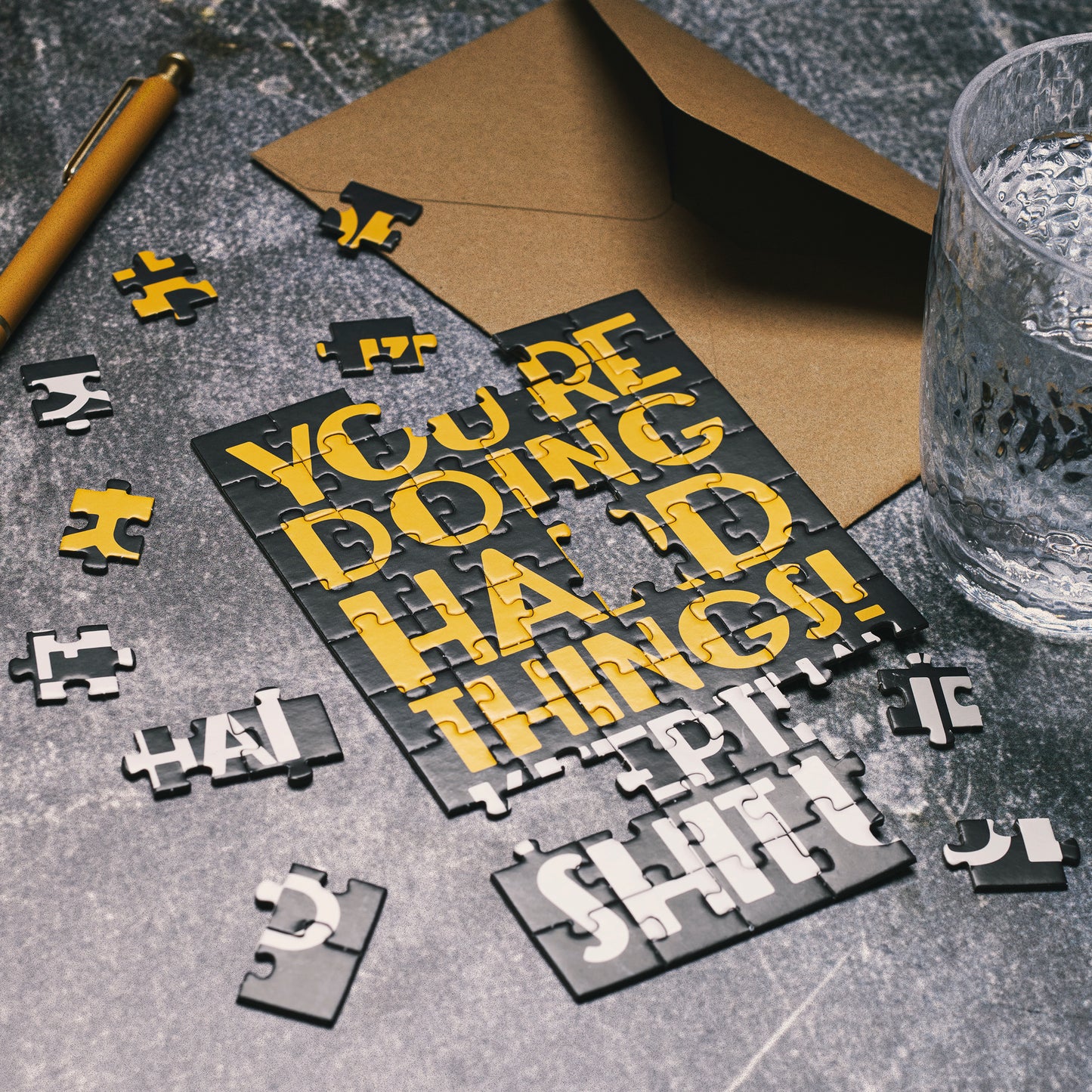Puzzle with motivational text on a table with a pen and glass of water.