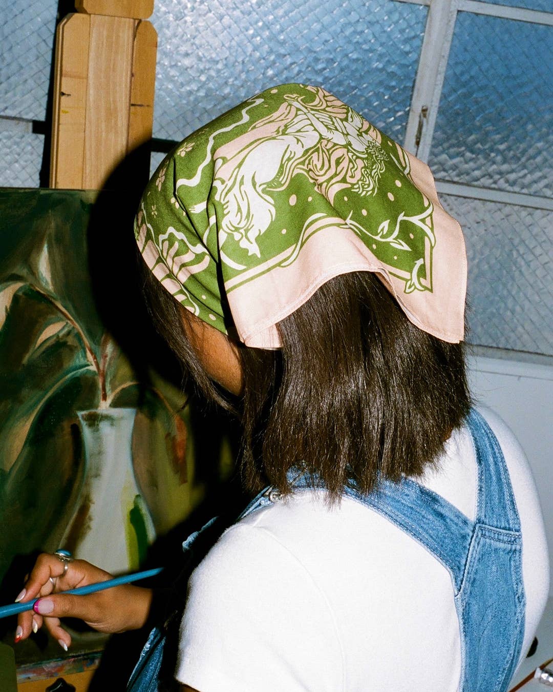 Person wearing a green patterned headscarf in an indoor setting