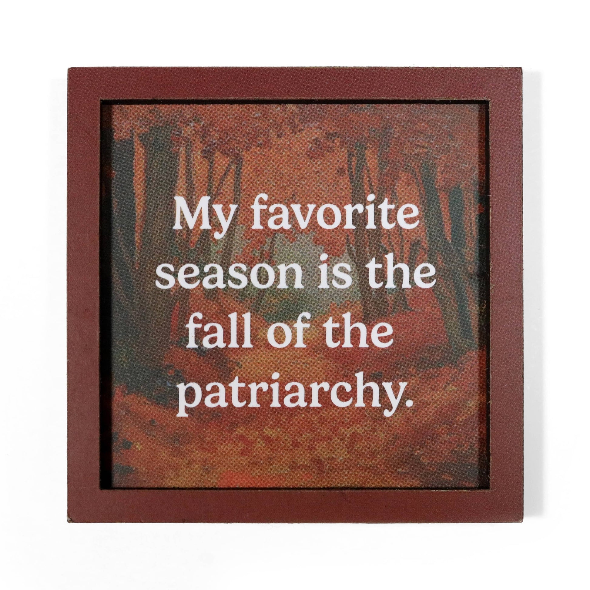 A square framed magnet with a reddish-brown border and an autumn forest artwork in the background. White text across the center reads, "My favorite season is the fall of the patriarchy.