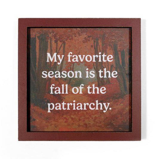 A square framed magnet with a reddish-brown border and an autumn forest artwork in the background. White text across the center reads, "My favorite season is the fall of the patriarchy.