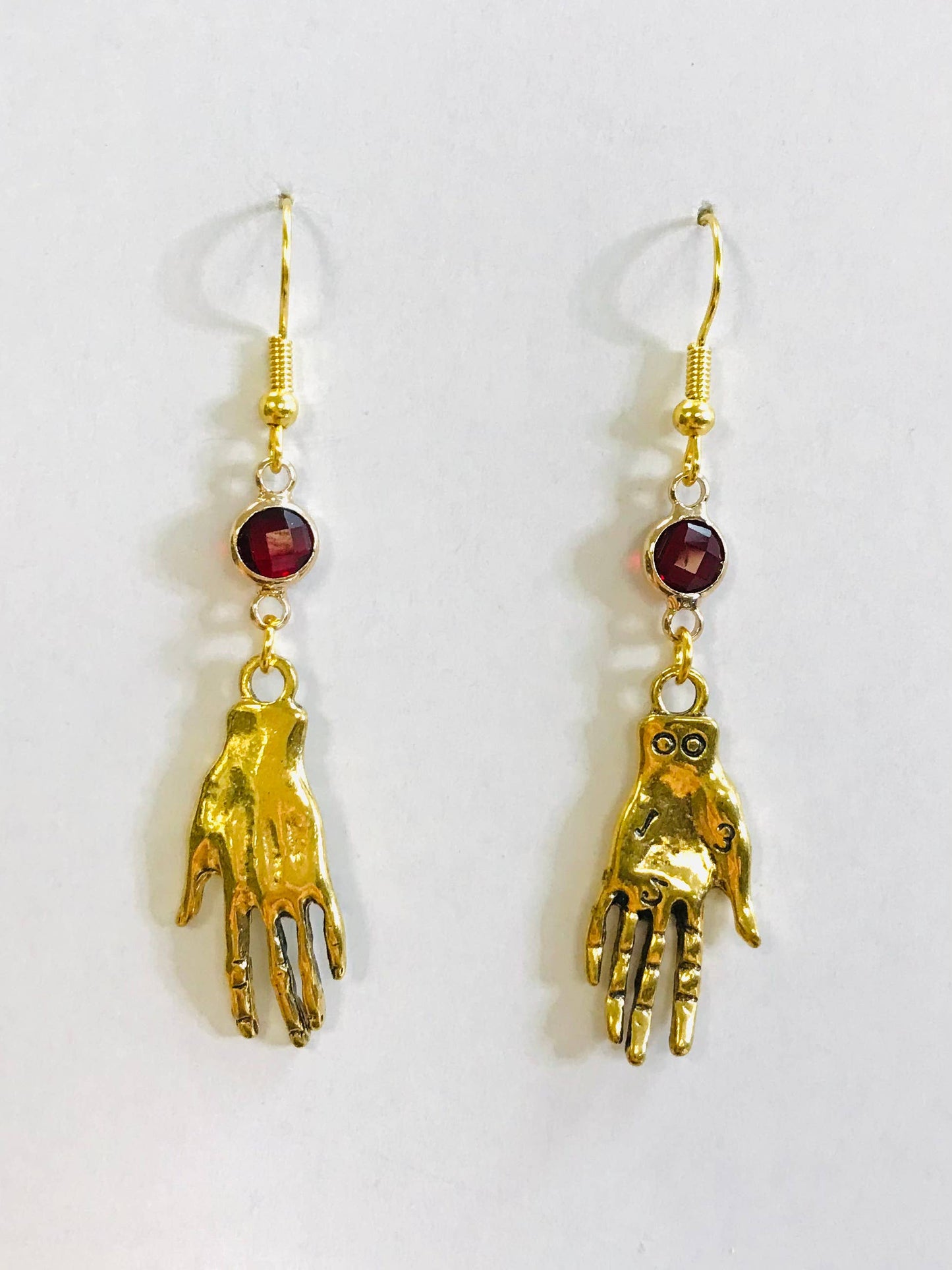 Gold hand-shaped earrings with red gemstones