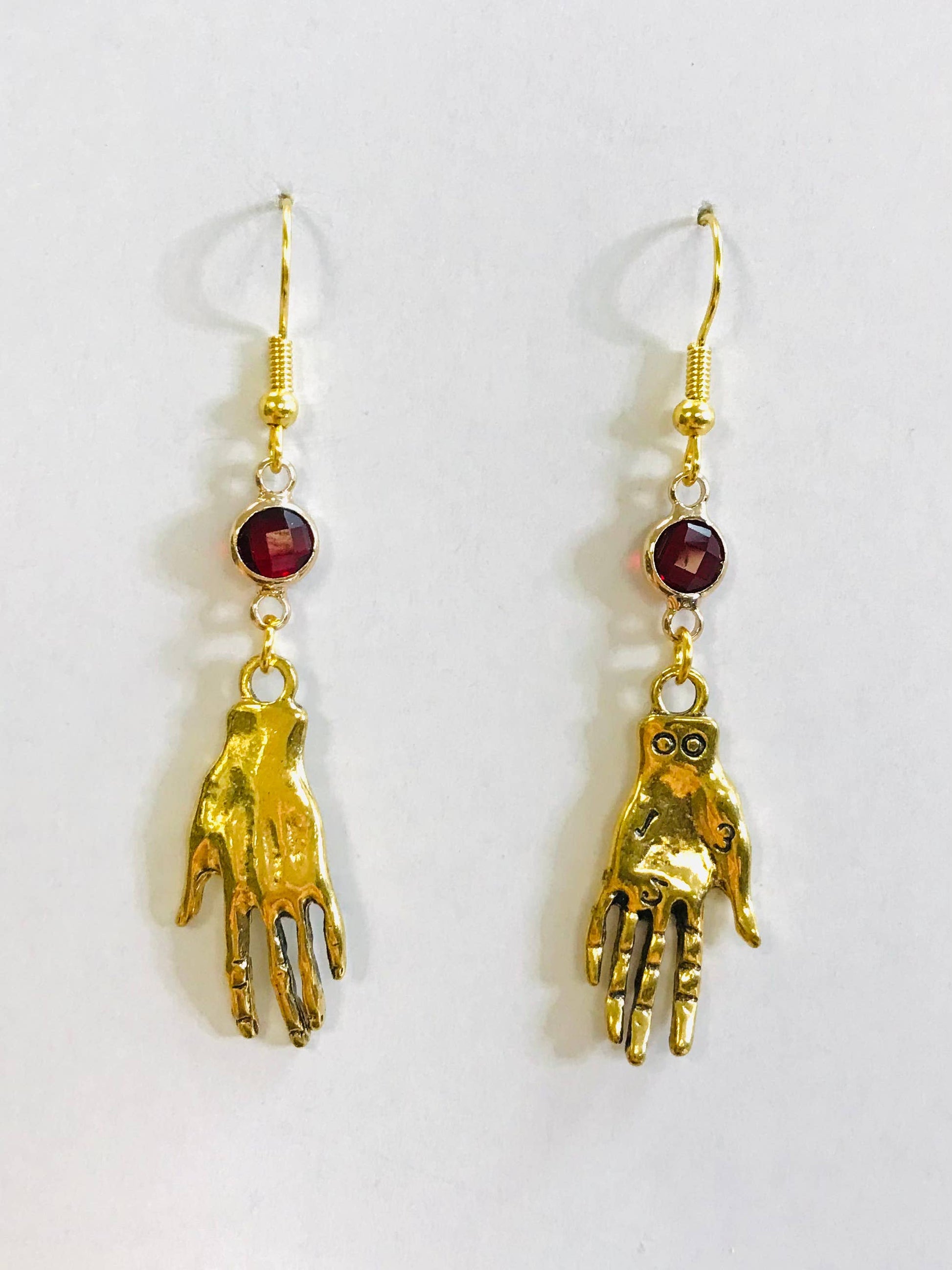 Gold hand-shaped earrings with red gemstones
