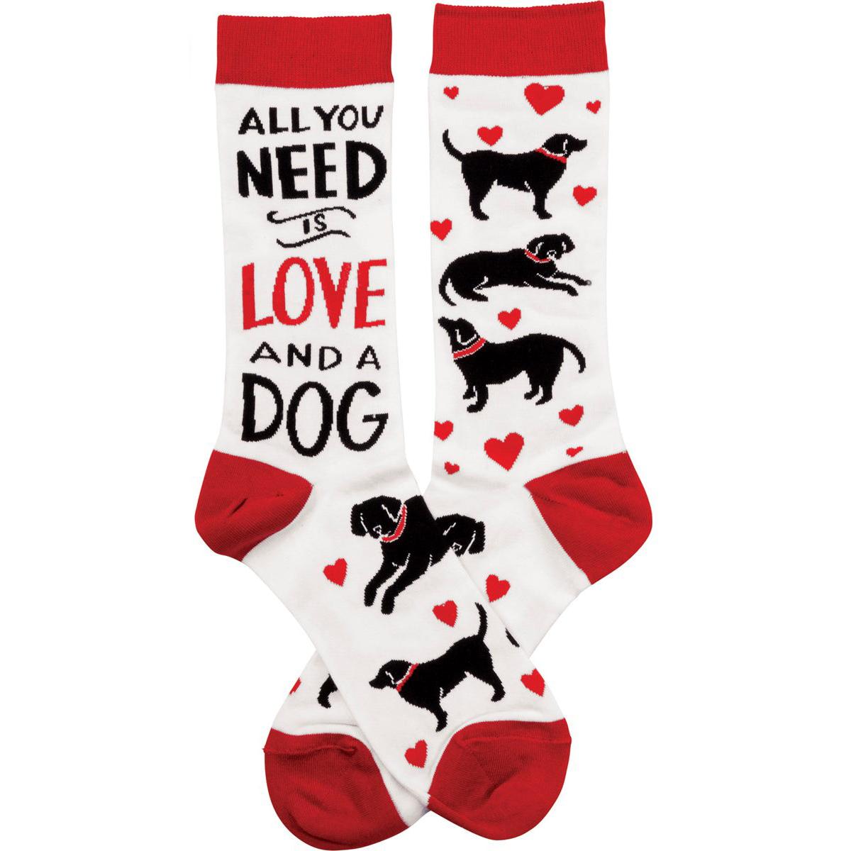 Pair of socks with dog illustrations and text 'All you need is love and a dog' on a white background.